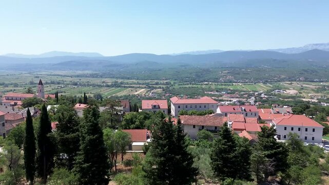 4K Aerial Drone Video Flying Over Imotski, Croatia, Revealing Cityscape and Distant Majestic Mountain Range on a Clear Day