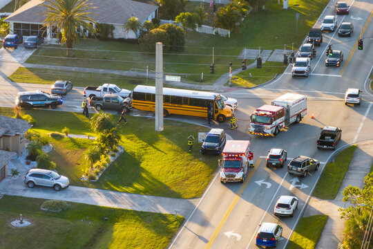 Car and school bus accident on highway road in Florida. Emergency services personnel helping victims of vehicle crash on city street in USA