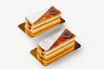 Two mille-feuille pastries with custard and chocolate resting on golden plates