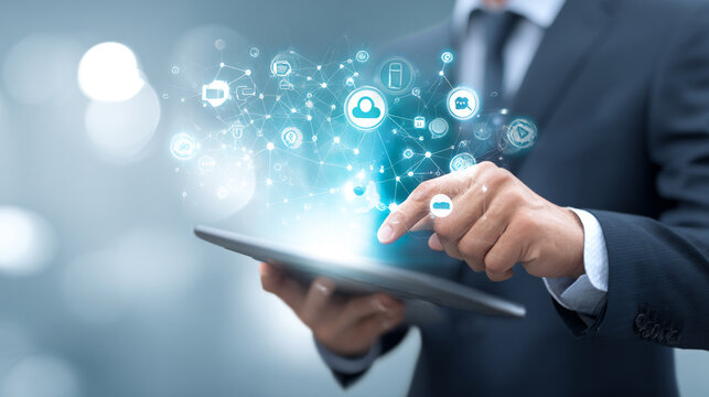 A businessman in a suit uses a tablet, his finger interacting with a cluster of glowing digital icons and applications