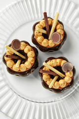 Delicious caramel and chocolate pastries decorated with gold flakes on white plate