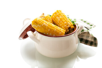 Two boiled corn cobs with dill on a white background