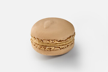 Single coffee macaron resting on white background