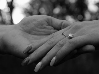 Black and White Close-Up of Man Holding Woman’s Hand to Showcase Engagement Ring