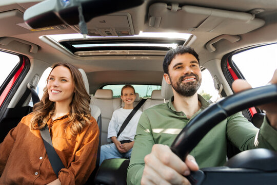 Happy parents with child daughter riding car, traveling by automobile together, family of three enjoying road trip