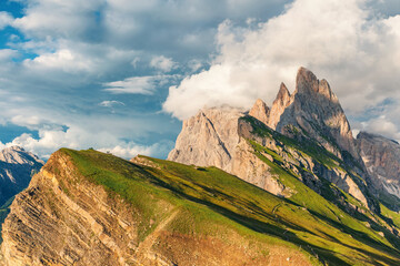 Seceda mountain ridge in the Italian Dolomites Alps at sunset, Trentino Alto Adige, Italy. Mountain landscape with jagged peaks and green slopes under cloudy sky in Dolomiti, South Tyrol
