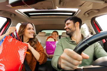 Happy family of three driving home after shopping in mall, parents and daughter sitting inside car,...