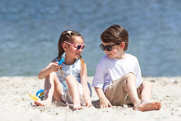 Barefoot happy children boy and girl play on the beach on summer holidays, look at each other....