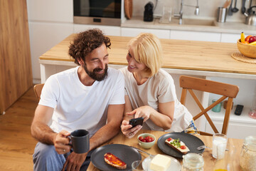 A couple shares a delightful breakfast experience in a warm kitchen, filled with laughter and joy...