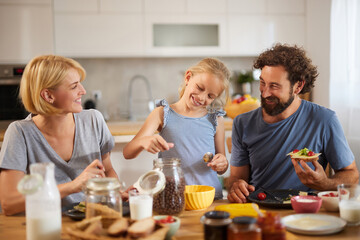 A family gathers in their bright kitchen, with a girl measuring ingredients, while her parents...