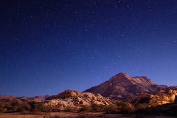 Obraz premium Celestial Desert Nightscape: A Starscape Above Majestic Mountains and Rocky Terrain