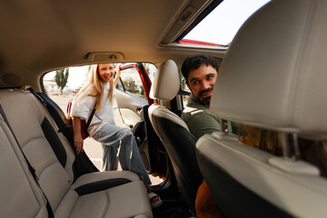 Father taking her daughter from school, girl sitting at back seat in car while dad sitting at drivers seat and turning back to girl