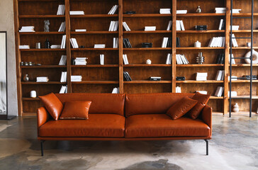 Modern orange leather sofa in stylish library for contemporary interior design and home decor...