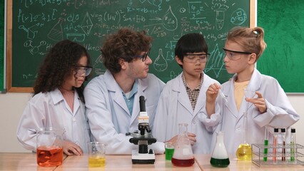 Skilled child hold tube while doing experiment while smart teacher explain and analyze chemical...