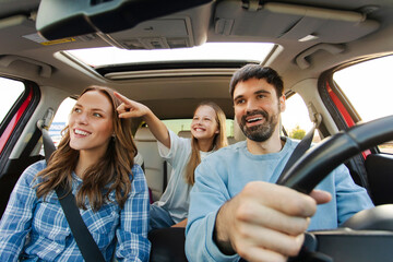 Cheerful family enjoying car trip, preteen girl pointing at road, happy parents and child spend...