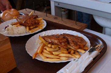 Kotlette mit Pommes liegen auf einem weißen Teller