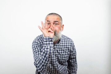 Bearded senior man making ok sign covering mouth showing approval sign