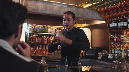 Asian smart bartender shaking mixed cocktail preparing to serve at luxurious counter preparation making special drink serving to customer fronted bar. Special refresh drink nightlife luxury. Vinosity.