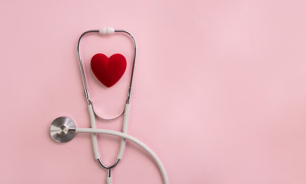 White stethoscope and red decorative heart on pink background. Medical calendar or banner for cardiology hospital or clinic. Selective focus, copy space