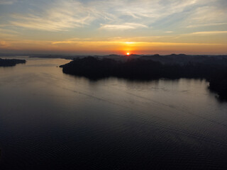 Orange sun setting between mountains behind large lake