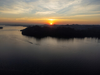 Orange sun setting between mountains behind large lake