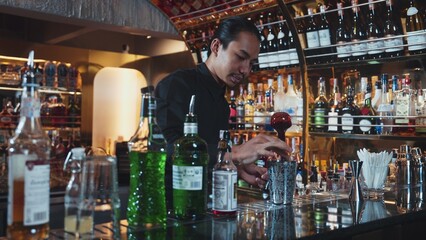 Asian bartender pouring mixed cocktail juice liqueur all ingredient into sliver shaker alcohol...