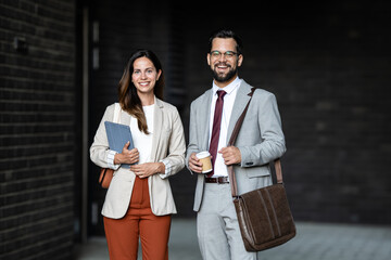 Business partners walking together and holding tablet and coffee