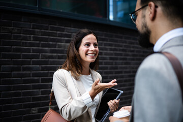 Businesswoman holding tablet gesturing while talking to businessman outdoors