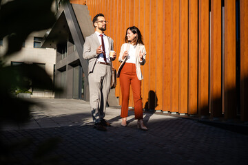 Business people walking and talking during coffee break outdoors