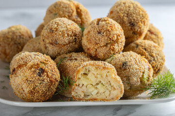 Crispy potato croquettes with tuna, cheese and dill on white plate.