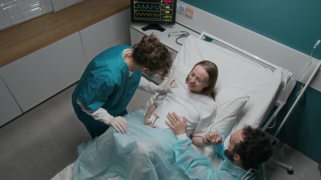Full high-angle shot of pregnant Caucasian woman breathing, pushing, screaming, while giving birth to baby in hospital, then fainting from painful contraction, midwife bringing oxygen mask