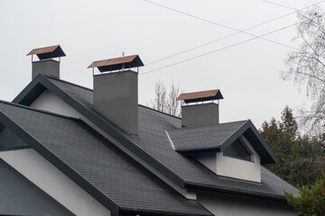A residential building showcases modern architectural design with distinctive chimneys topped with...