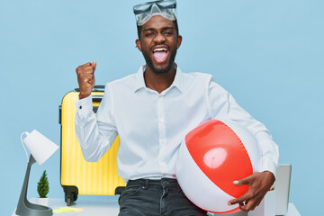 Smiling man with dark skin, wearing white shirt and sunglasses on head, holding a red and white...