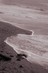 Seascape. Wild beach of Portugal. Waves in motion. Stones washed by water. Abstract background with space for insertion. Wallpaper. Postcard. Poster