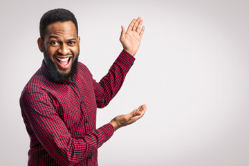 Excited African Man Showing Blank Space Aside Gesturing With Hands Standing Over White Background....