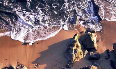 Seascape. Wild beach of Portugal. Waves in motion. Stones washed by water. Abstract background with space for insertion. Wallpaper. Postcard. Poster