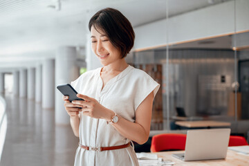 Asian mature business woman manager ceo using cell phone mobile app. Smiling eastern 40s years old...