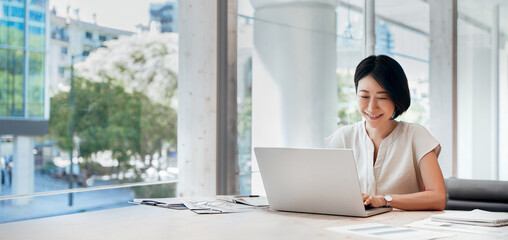 Middle-aged woman using computer technology for financial marketing work online. Mature Asian professional businesswoman analyst working concentrated on laptop pc at desk in office. Banner, copy space