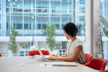 Middle-aged woman using computer technology for financial marketing work online. Busy mature Asian professional businesswoman analyst working concentrated on laptop pc at desk in office. Copy space