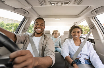 Black Parents And Daughter Posing Riding New Car Smiling To Camera Enjoying Road Trip. Family...