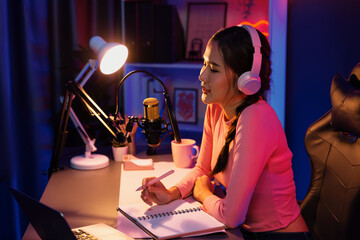 Smiling creative young beautiful Asian influencer talking in channel with positive podcast speech...