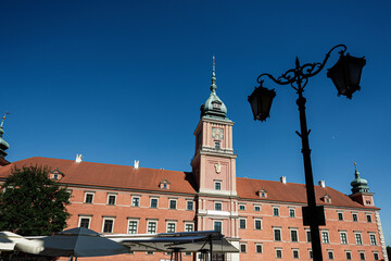 Historic building Royal Castle in Warsaw, Poland with lively square and clear blue sky