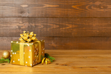 Golden gift box with christmas decor on wooden table