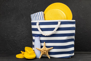 Blue beach bag with summer accessories on wooden table
