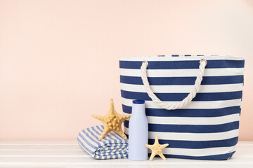 Blue beach bag with summer accessories on wooden table