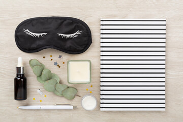 Sleeping mask with accessories on wooden background, top view. Sleeping routine concept