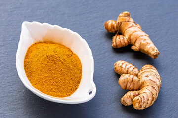 Turmeric Roots and Powder in White Bowl on Dark Slate – Natural Superfood and Culinary Spice