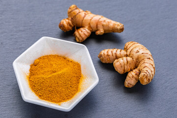 Turmeric Roots and Powder in White Bowl on Dark Slate – Natural Superfood and Culinary Spice