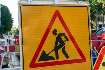 Construction warning sign indicating ongoing roadwork in an urban area during daytime