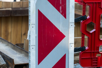Construction site warning sign indicating a change in direction for vehicles on a busy road